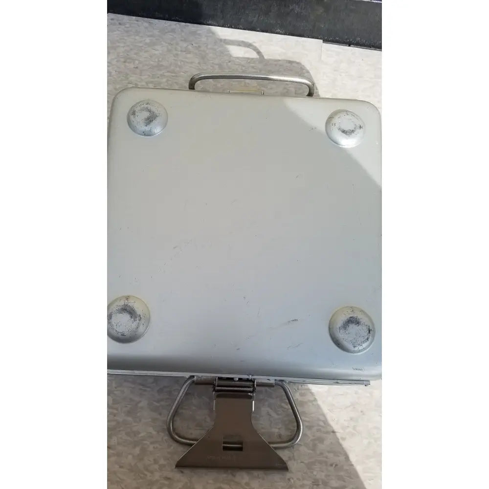 Silver metallic aesculap sterilization container without lid featuring sturdy handle and four circular foot pads