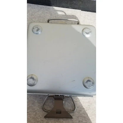 Silver metallic aesculap sterilization container without lid featuring sturdy handle and four circular foot pads