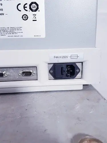 White plastic power input port with black plug and metal connector plate on the back of affymetrix genechip fluidics station 450