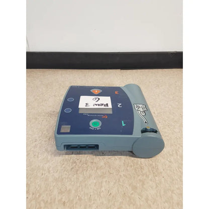 Blue-gray agilent heartstream fr2 semi automatic defibrillator with green power button and numbered front pads