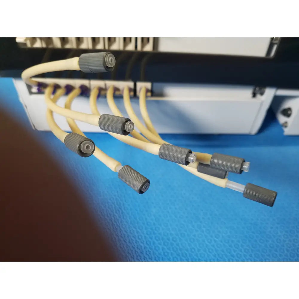 Beige and gray fiber optic cables with textured connectors on agilent technologies 810 peristaltic pump for reuse medical applications