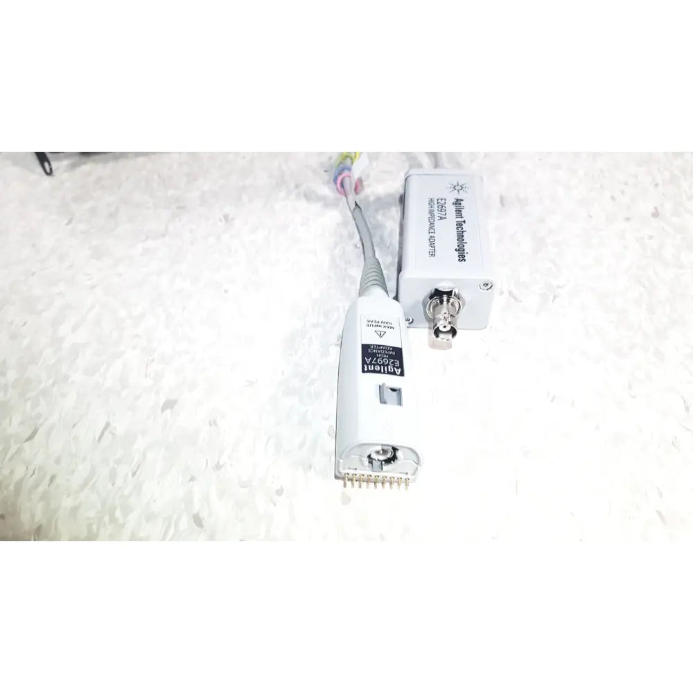 White agilent technologies e2697a high impedance adapter with gray cable and metallic connector with papers