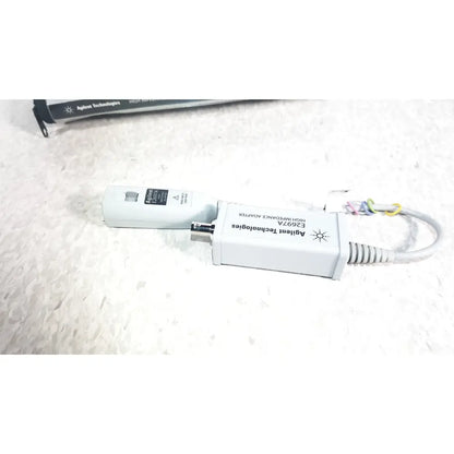 White agilent technologies e2697a high impedance adapter with coiled cable and attached connectors with papers