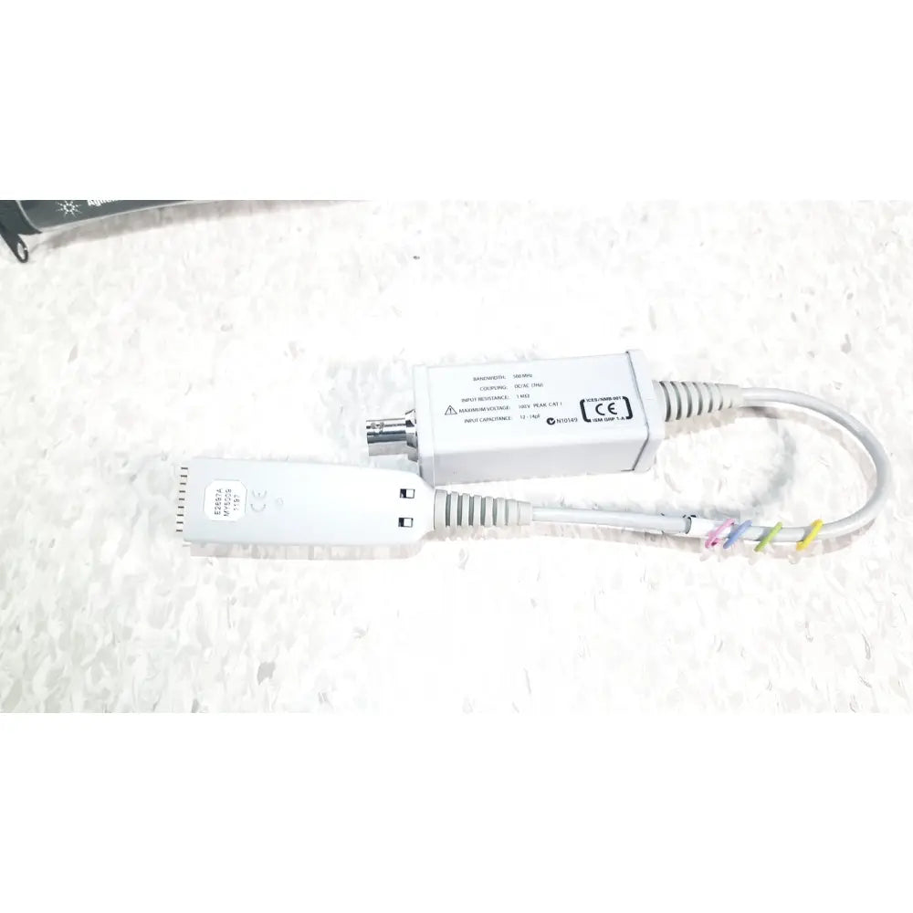 White agilent technologies e2697a high impedance adapter with coiled cables and colorful ties shown with papers