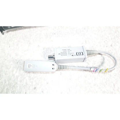 White agilent technologies e2697a high impedance adapter with coiled cables and colorful ties shown with papers