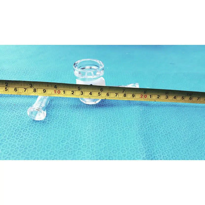 Clear glass airfree flushing adapter with cylindrical body and threaded neck beside measuring tape on blue surface for schlenk line glassware lab