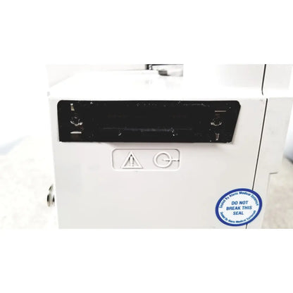 White medical device with black rectangular panel and blue circular seal showing back side of alariis pca model 8120 without keys