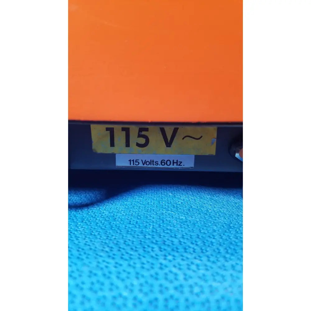 Orange alcatel drytel vacuum pump station with yellow 115 v label and white 115 volts sticker on electrical device