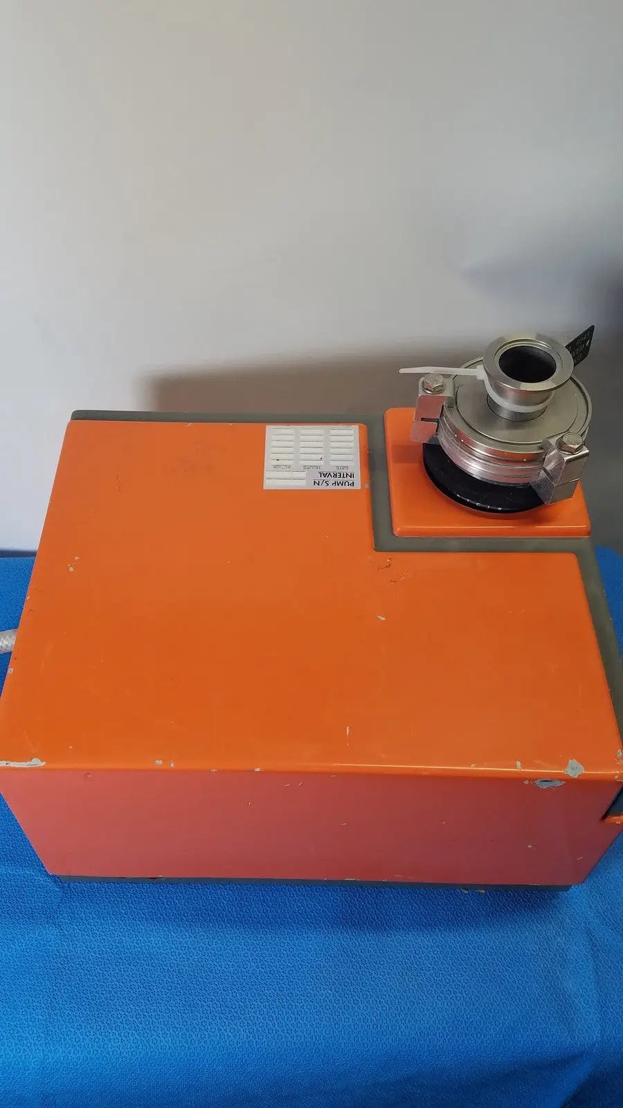 Orange industrial laser cutter with metallic cylindrical attachment on top of alcatel drytel 31 vacuum pump station