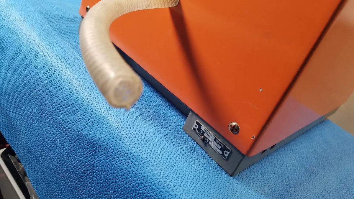 Orange alcatel drytel 31 vacuum pump station with translucent flexible hose attached for industrial vacuum pump use