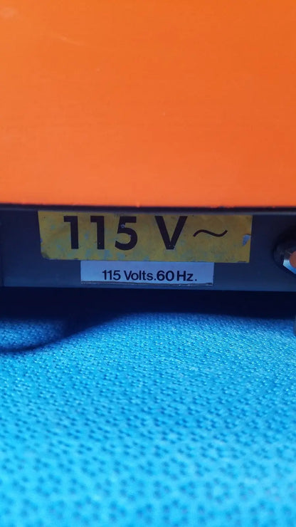 Orange alcatel drytel vacuum pump station with yellow 115 v label and white 115 volts sticker on electrical device