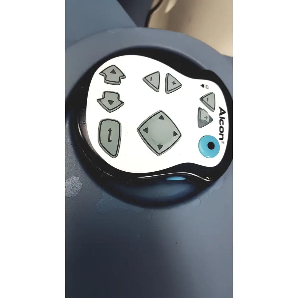A sleek white and black alcon infiniti vision system remote with gray directional and blue circular buttons