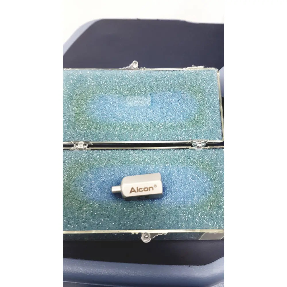 Silver alcon infiniti vision branded medical device with cylindrical body resting on blue foam inside open case