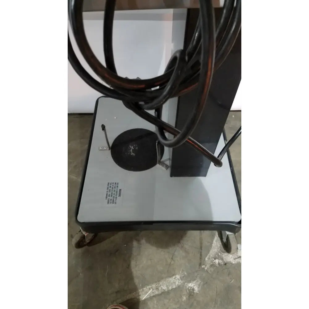 Black coiled cable on gray and black wheeled cart base of allied healthcare gomco 3040 aspirator back side view