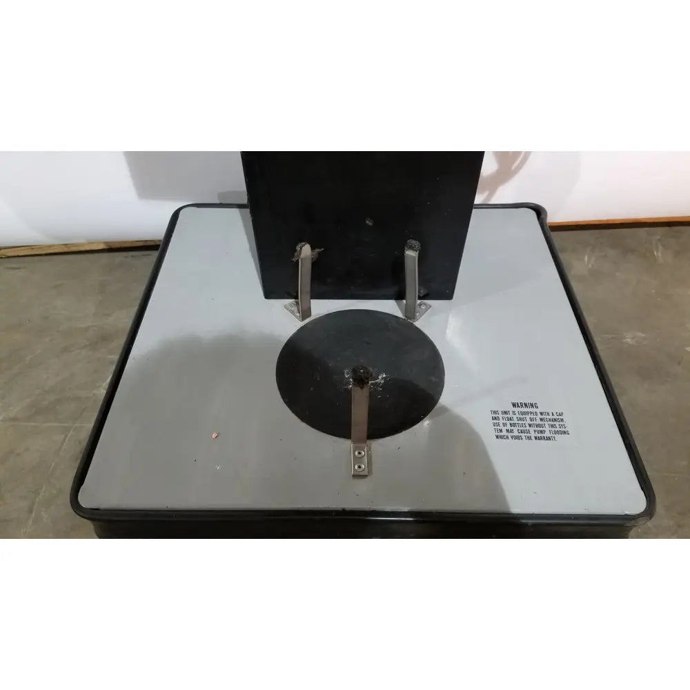 Black industrial-grade metal testing machine with circular platform and warning label for allied healthcare gomco 3040 aspirator