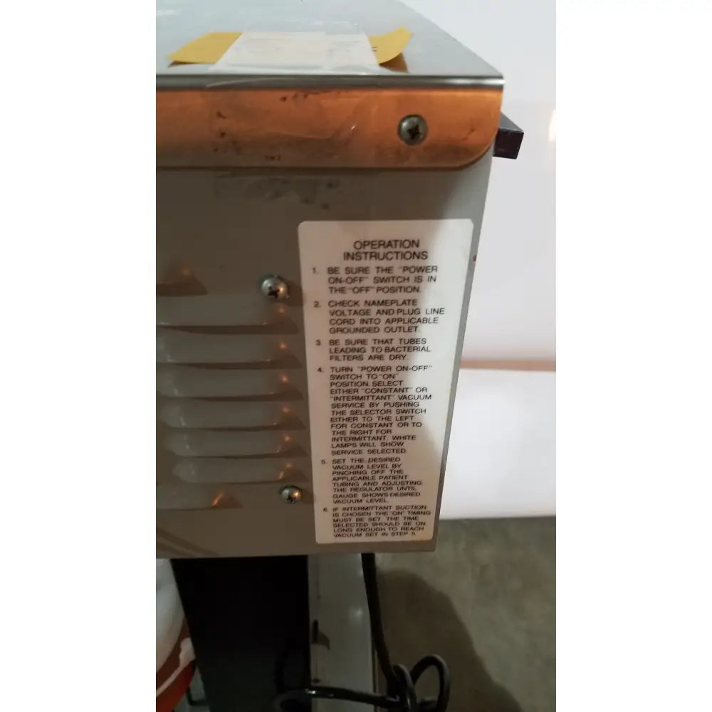 Metallic industrial vacuum cleaner with rusted orange top and silver body featuring operation label allied healthcare gomco model 6037 aspirator