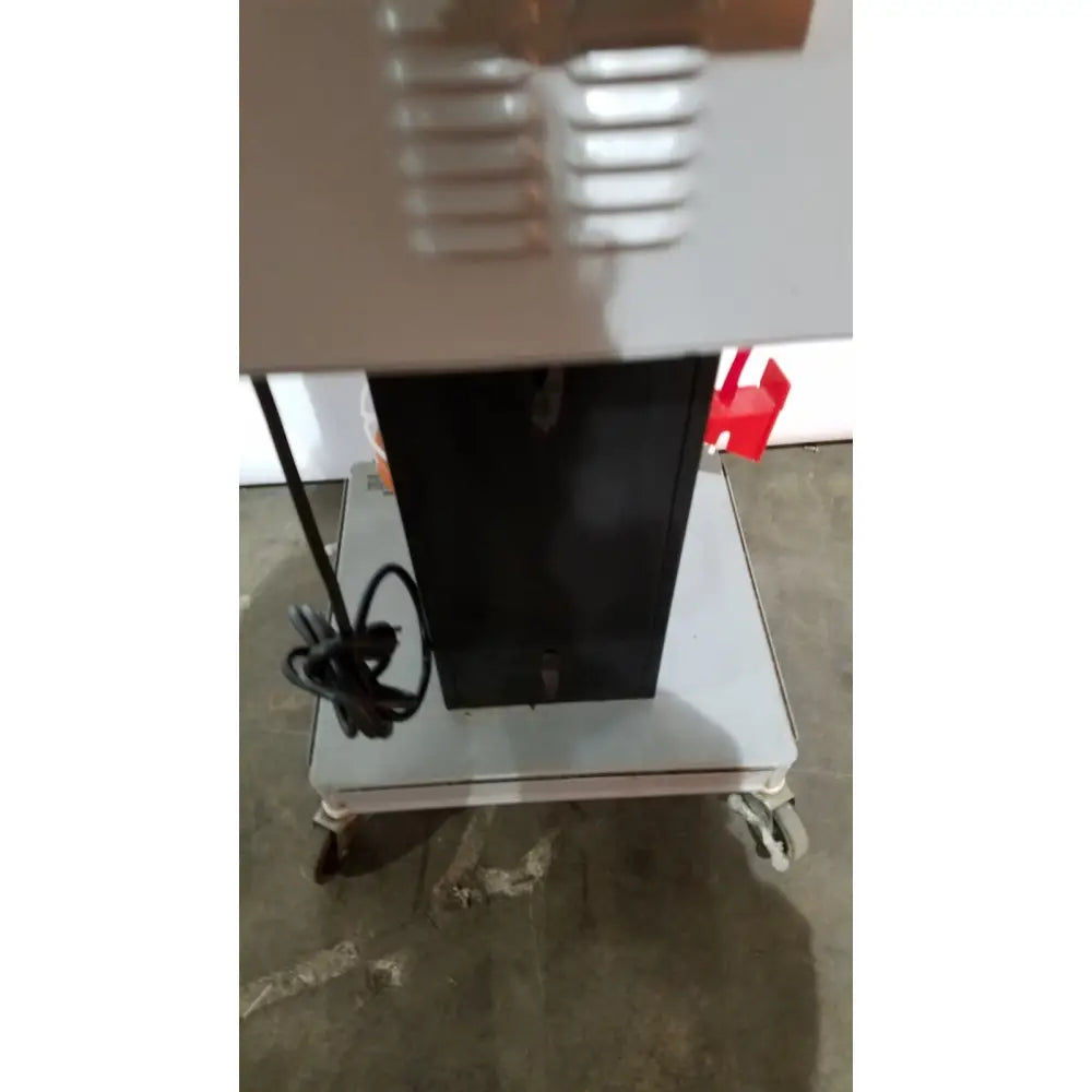 Black rectangular allied healthcare gomco model 6037 aspirator with silver vented top panel mounted on a wheeled cart