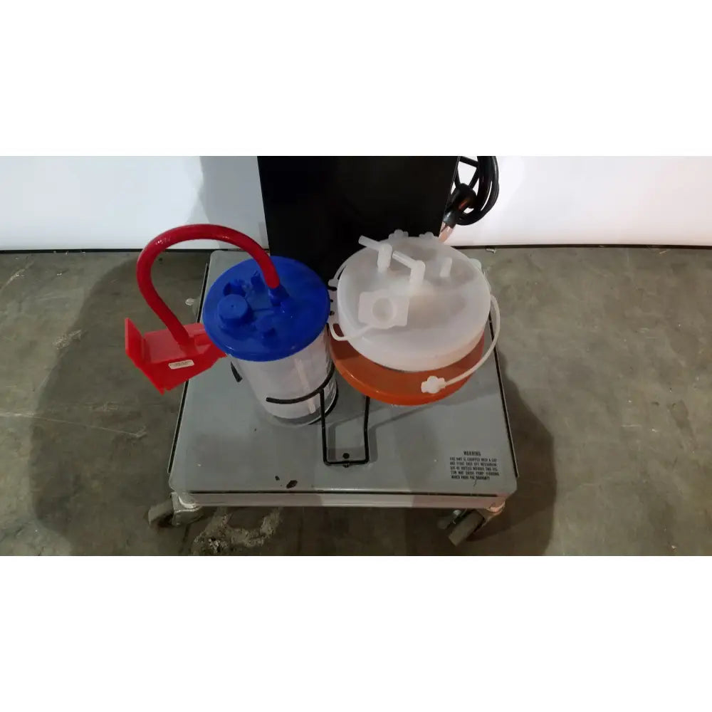 Red and blue suction canisters mounted on a gray cart in allied healthcare gomco model 6037 aspirator for medical use