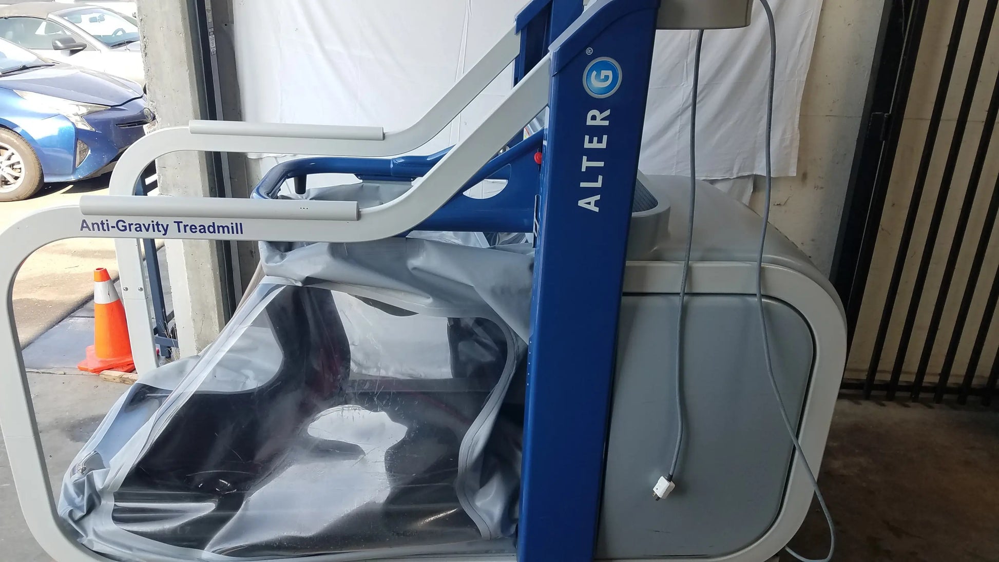 Blue and gray alter g m320 anti-gravity treadmill with adjustable body-weight support and transparent protective cover