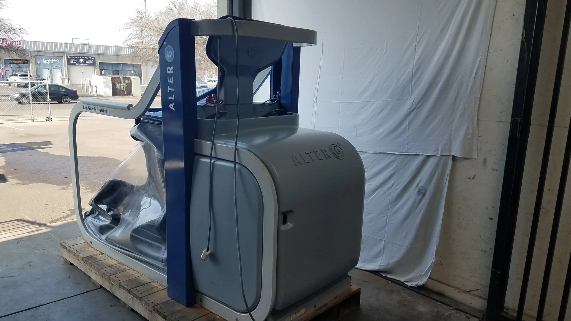 Alter G M320 anti-gravity treadmill in gray and blue with transparent protective cover and adjustable body-weight support