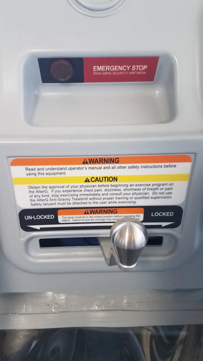 Silver metallic emergency stop button with red label on alter g m320 anti-gravity treadmill panel for adjustable body-weight support