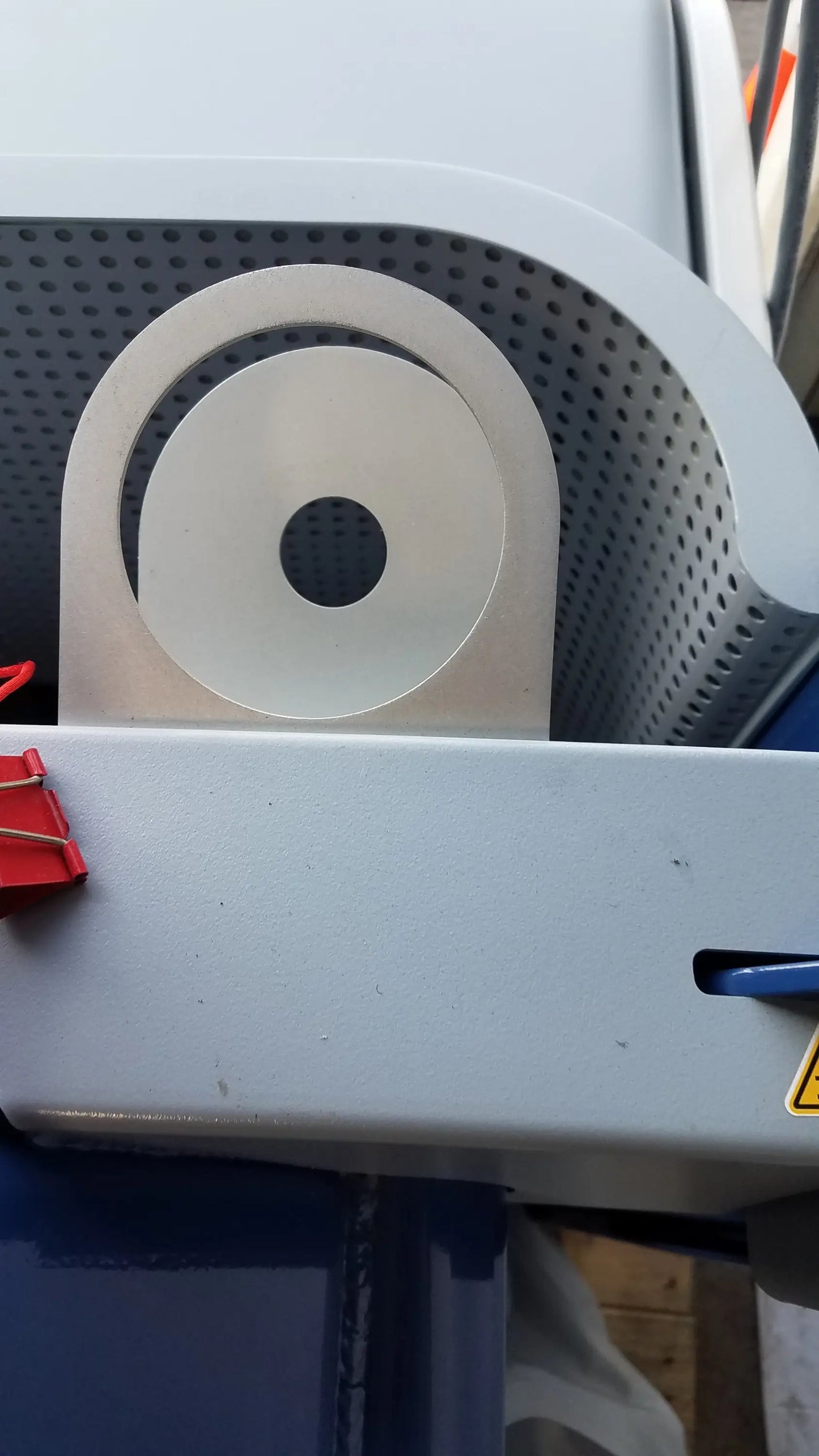 White circular component with central hole mounted on perforated gray surface of alter g m320 anti-gravity treadmill with adjustable body-weight support