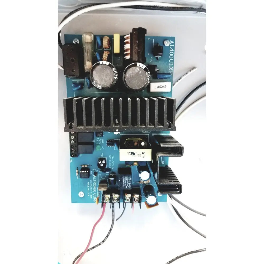 Blue circuit board with black heat sinks and silver capacitors in altronix al400ulx power supply charger 12vdc or 24vdc