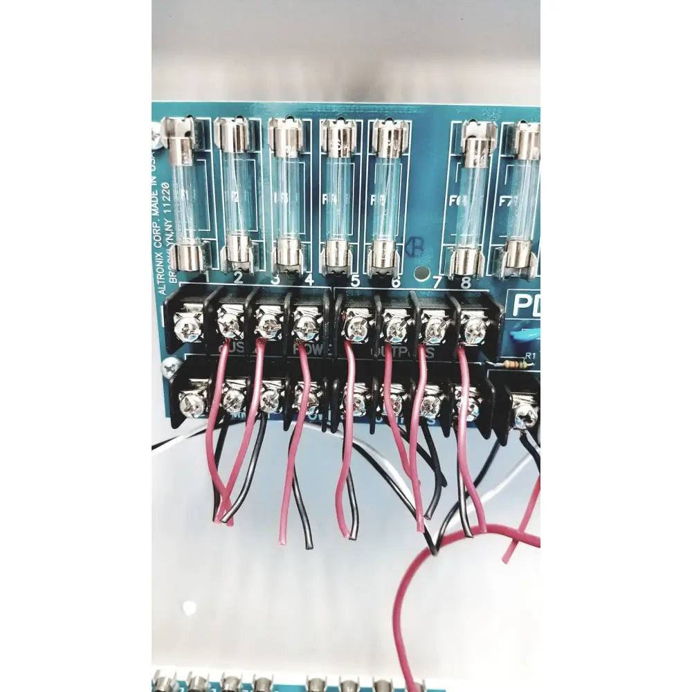 Blue circuit board of altronix smp5ctx high current power supply with eight glass fuses and red and black wire connections