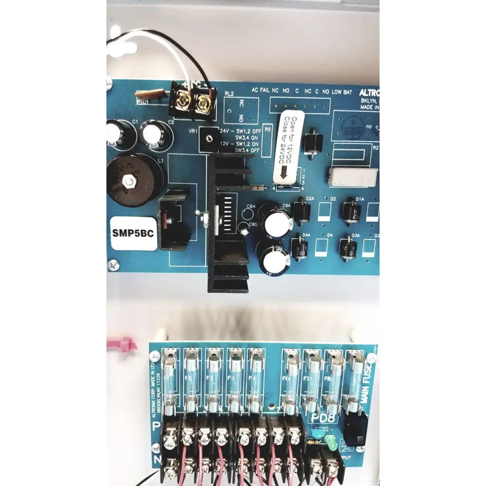 Blue circuit board with white labels and black components of altronix smp5ctx high current power supply charger