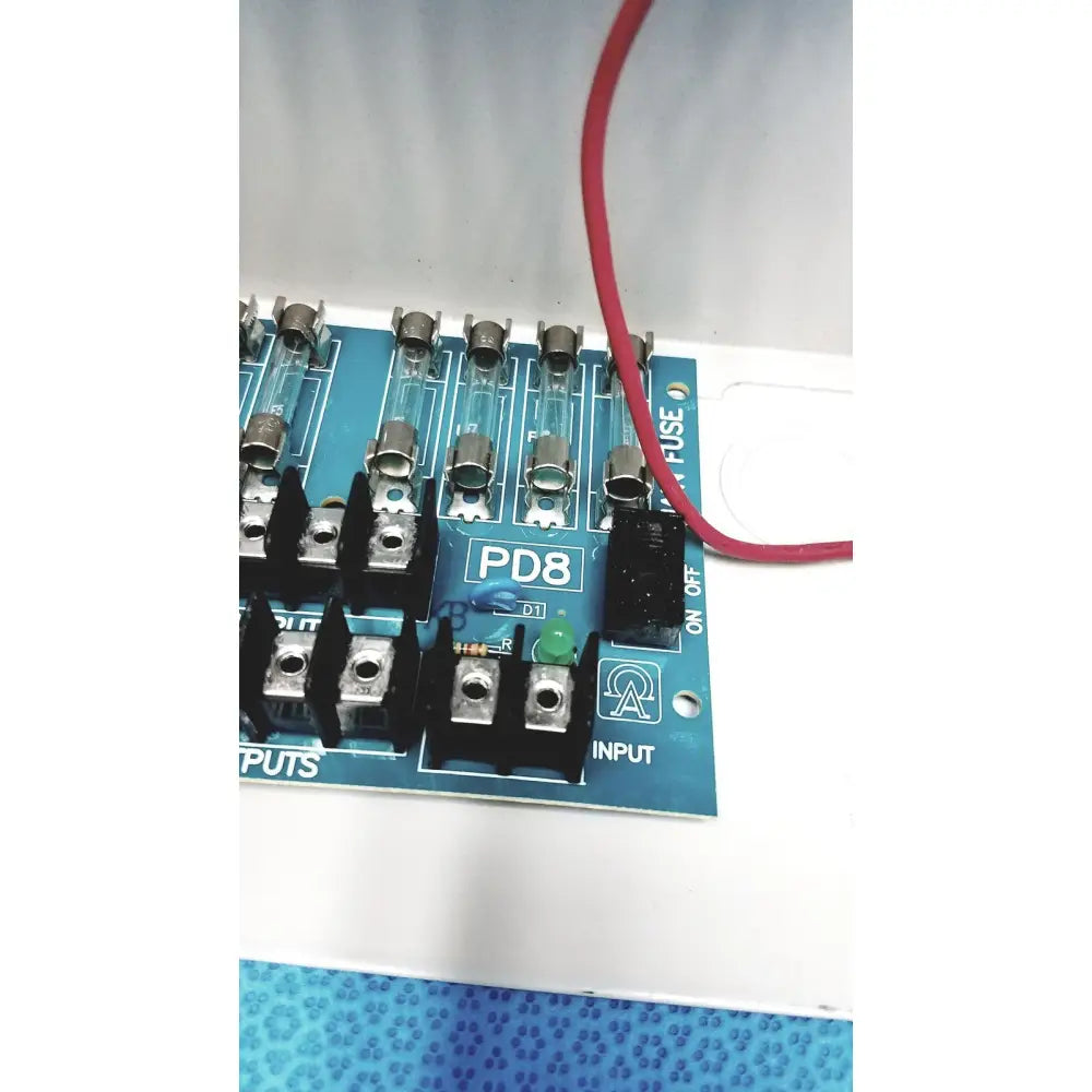 Blue pd8 circuit board with glass fuses and black terminal blocks in altronix smp5ctx high current power supply charger