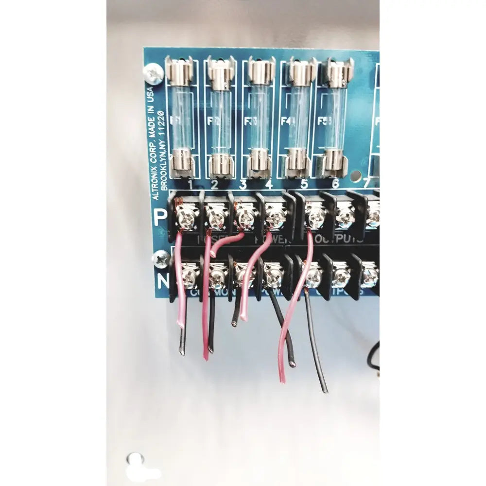 Blue altronix smp5ctx power supply circuit board with six glass fuses and black terminal blocks connected by pink and black wires