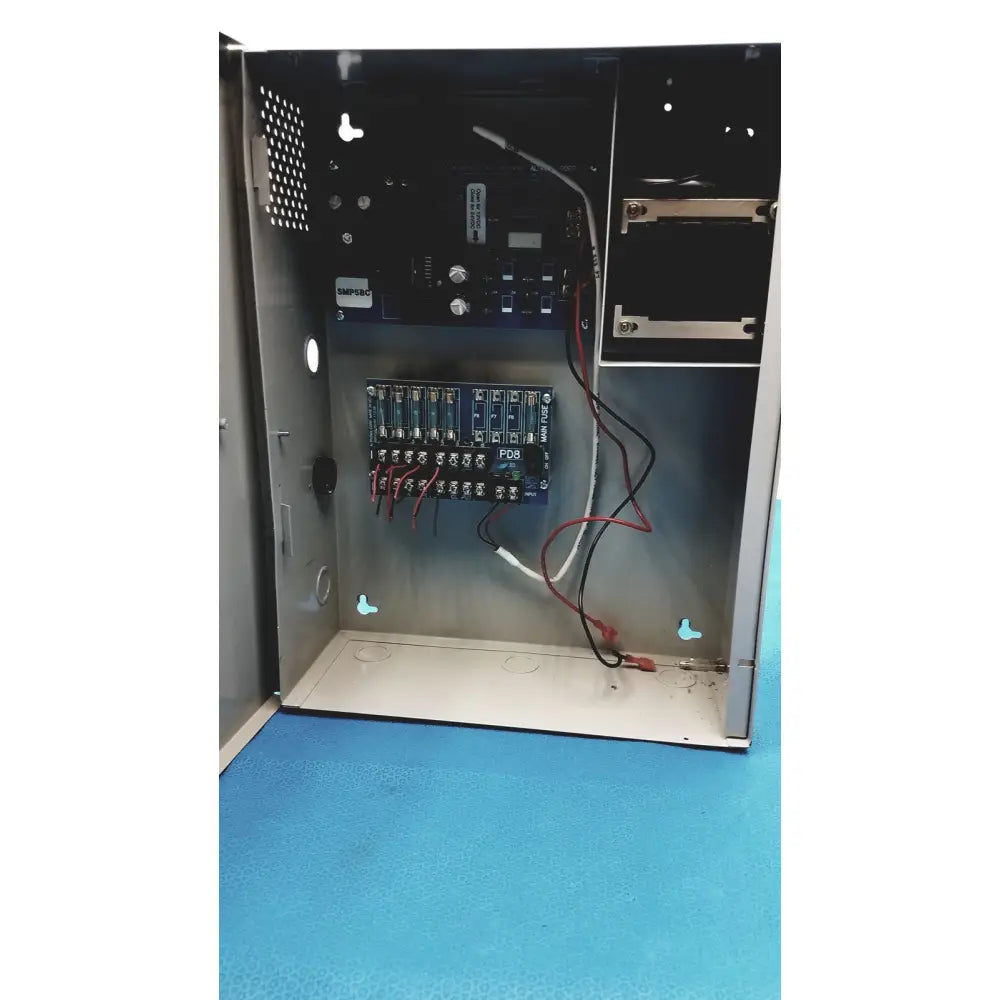 Metallic gray altronix smp5ctx power supply with blue circuit boards red and black wiring and white pdr label mounted inside
