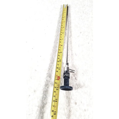 Silver surgical american cystoscope makers FO-8168M microlens with black handle and engraved markings beside yellow tape measure