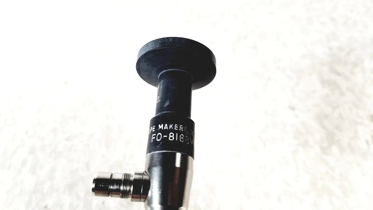 Black cylindrical medical device with metallic threaded connector labeled de maker fo-8169 by american cystoscope makers