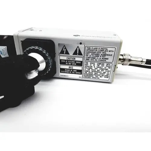 White rectangular electronic adcshr2412n with black rotary dial and silver connector showing warning labels on side panel