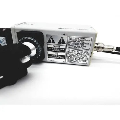 White rectangular electronic adcshr2412n with black rotary dial and silver connector showing warning labels on side panel