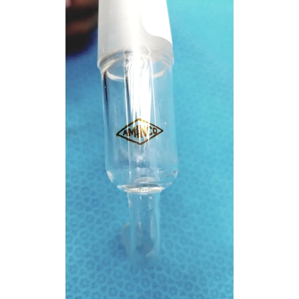 Clear glass volumetric flask with white stopper and gold aminco logo shown with aminco 250mm bent glass hose inlet adapter
