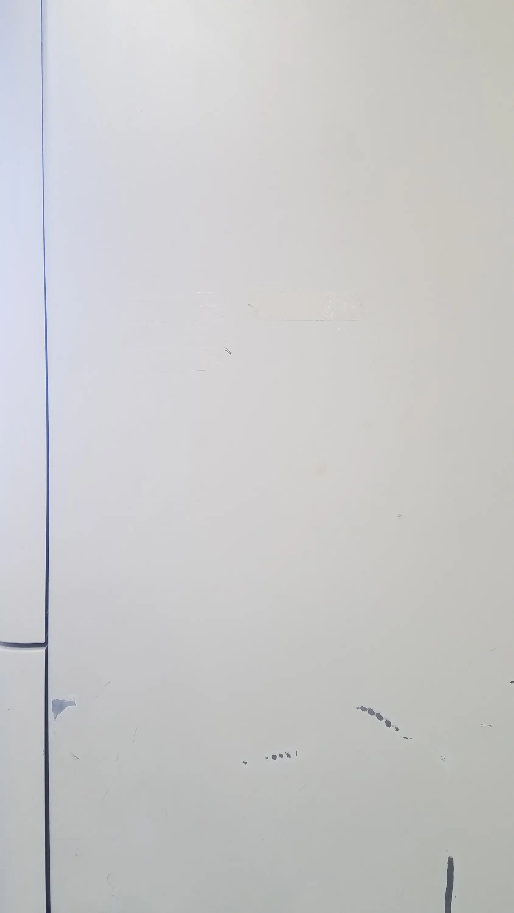 A plain white door with a vertical seam and minor scuff marks on the amsco steris v-pro max low temperature sterilization system