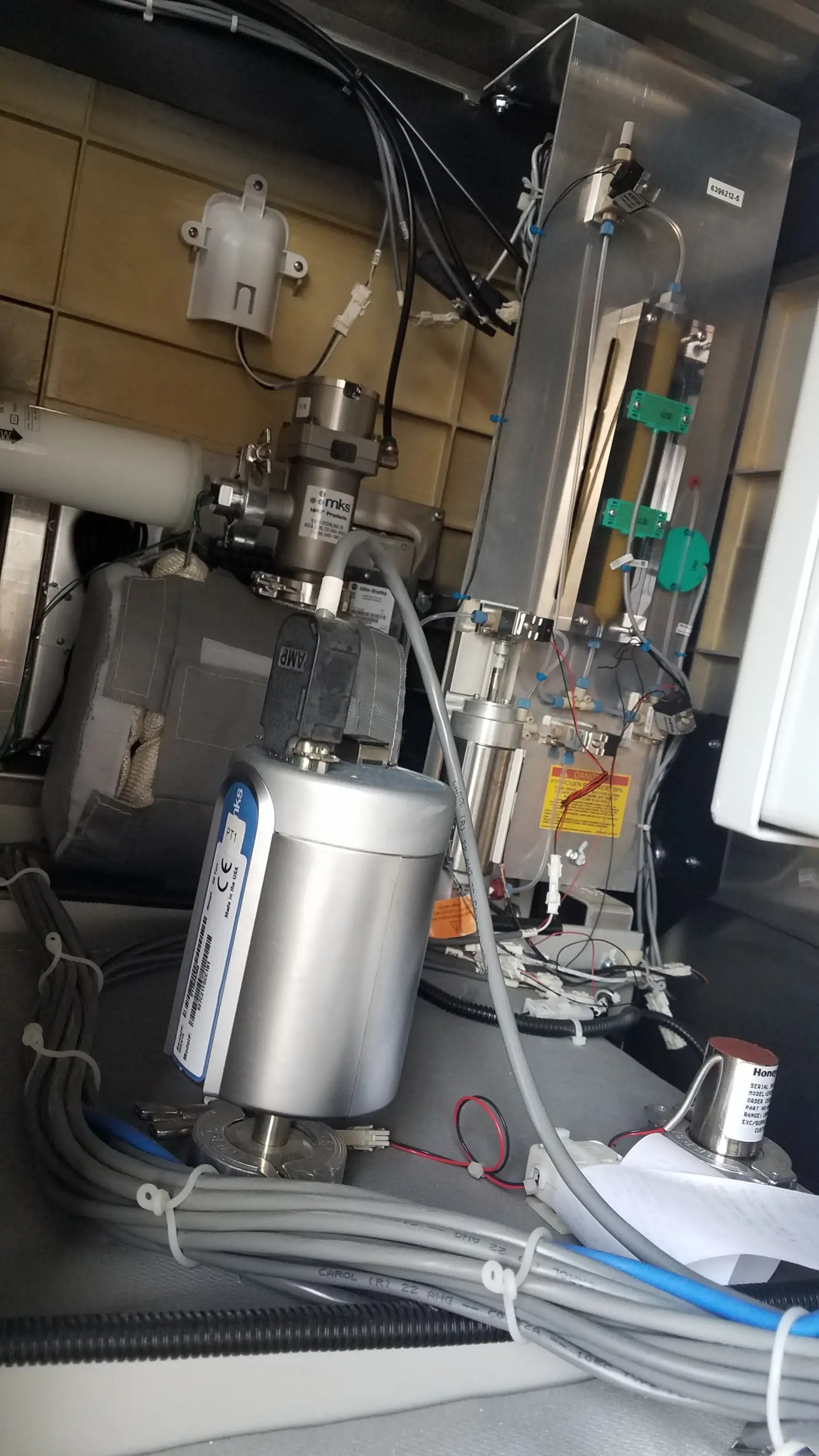 Silver cylindrical pump with blue and white labeling on metallic base in AMSCO Steris V-Pro Max low temperature sterilization system