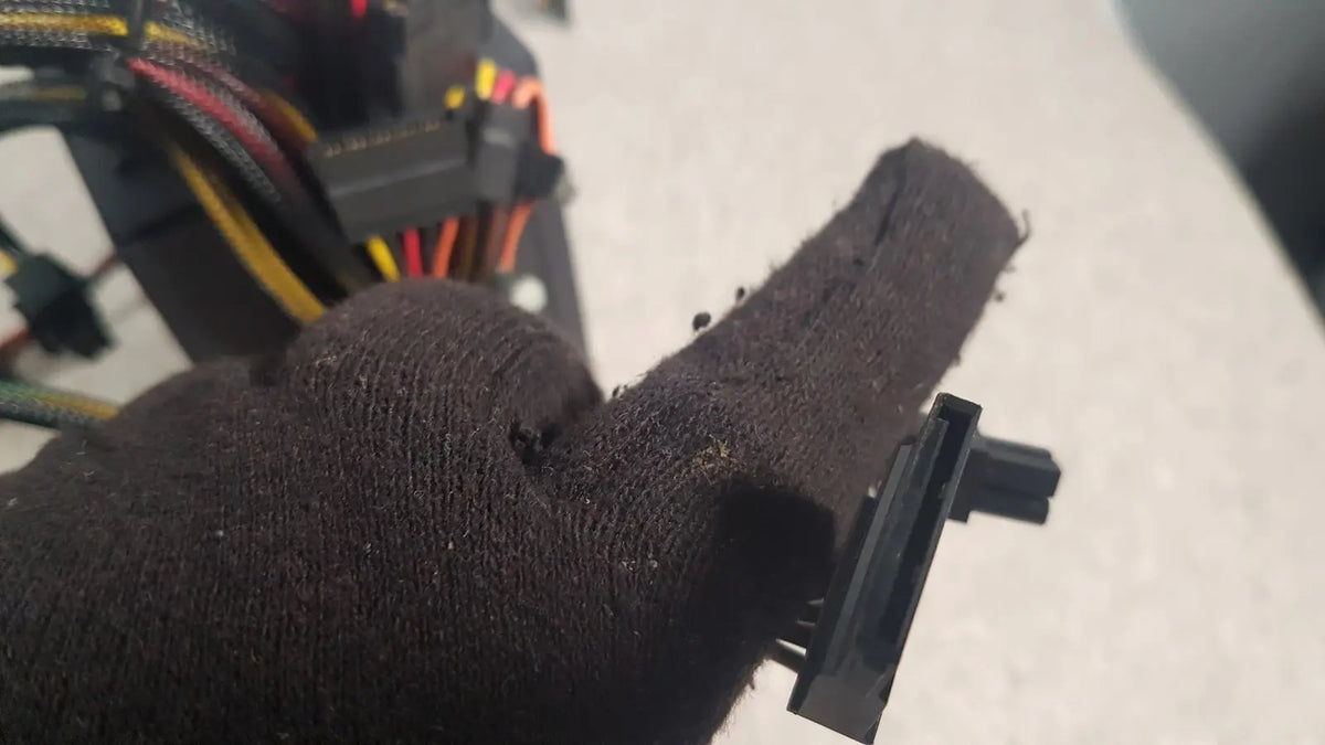 Black textured fabric glove holding black plastic connector of antec truepower 550w black switching power supply