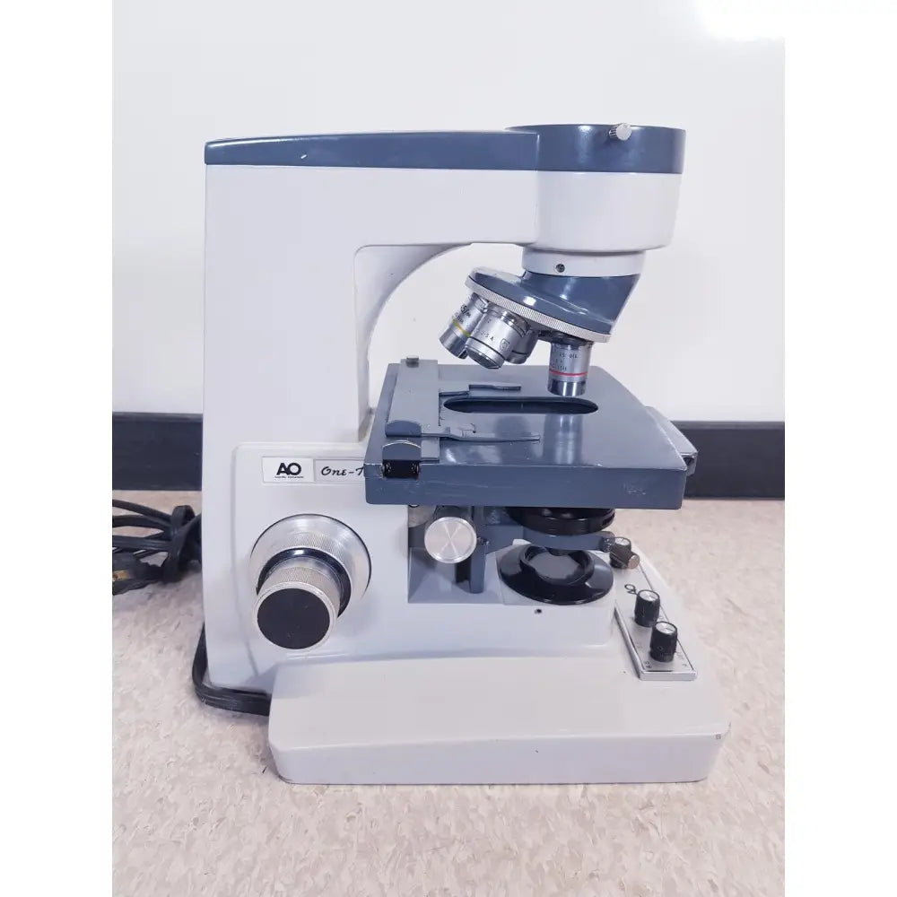 A vintage ao scientific instruments one-ten illuminator model 1130a compound microscope with silver lenses and black dials