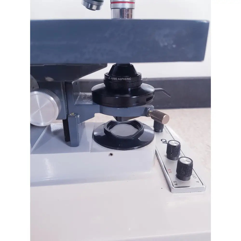 Black abbe aspheric microscope objective lens with silver metallic accents and matte finish by AO Scientific Instruments one-ten illuminator model 1130A