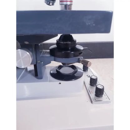Black abbe aspheric microscope objective lens with silver metallic accents and matte finish by AO Scientific Instruments one-ten illuminator model 1130A