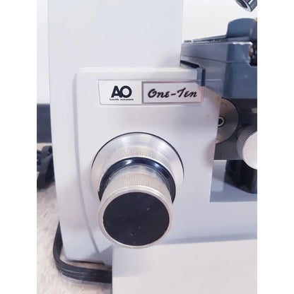 White AO scientific instruments one-ten microscope with silver-ringed focus knob and black central dial illuminator model