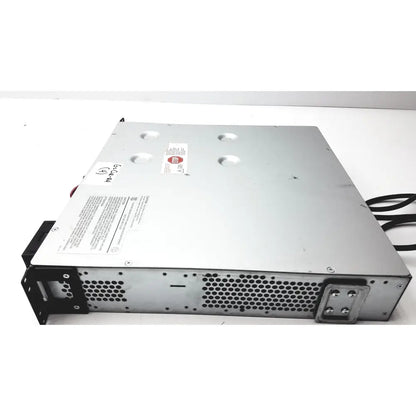 Silver metal server rack with black perforated panels and red sticker on top of schneider electric smart-ups smt1000rm2u