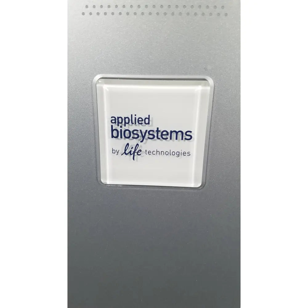 A sleek silver-framed white logo plaque displaying applied biosystems by life technologies on applied biosystems quantstudio dx instrument