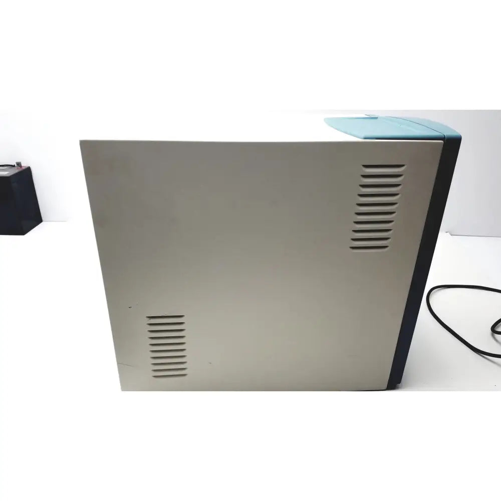 Beige and teal desktop printer with vertical ventilation slits on sides showing back view applied precision introduces arrayworxe biochip reader