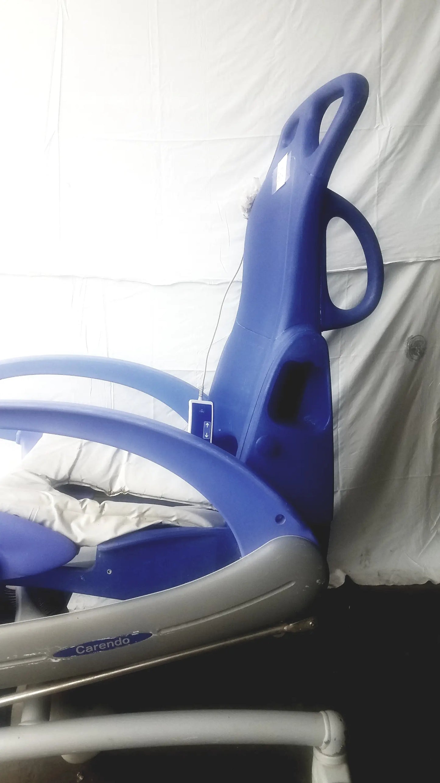 Blue and gray Arjo Carendo multipurpose hygiene chair with padded headrest and armrests designed for medical use
