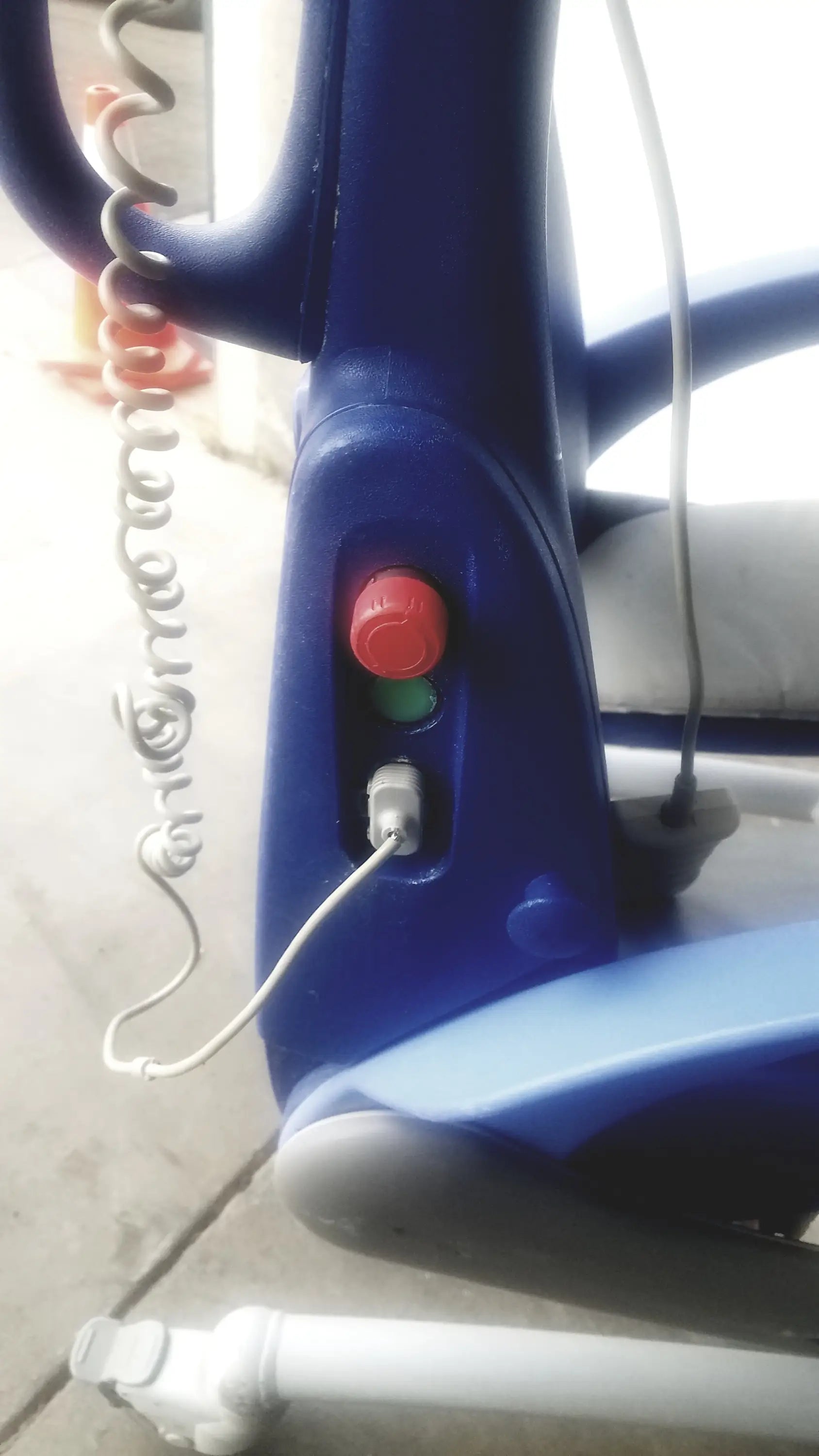 Blue plastic arjo carendo multipurpose hygiene chair with red and green buttons and coiled white cord on handlebar