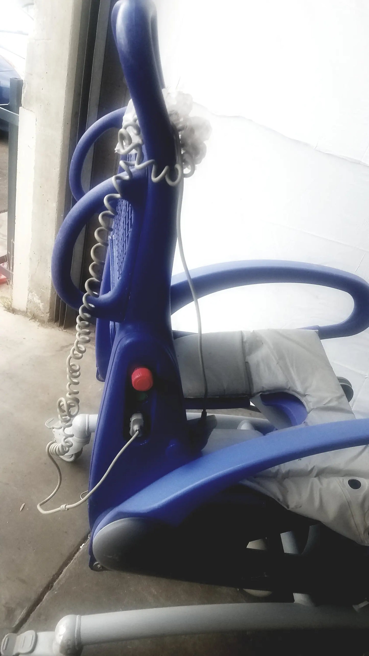 Blue plastic arjo carendo multipurpose hygiene chair with coiled cord and red button for effective multipurpose hygiene